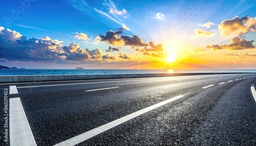 Open road leading towards the ocean at sunset with vibrant blue sky and clouds, promising adventure and travel