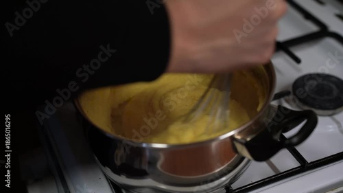 Caucasian man cooking , stir up polenta , making dinner.