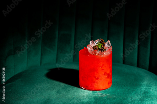 Φωτογραφία A vibrant red cocktail with crushed ice and a blackberry garnish, set on a green