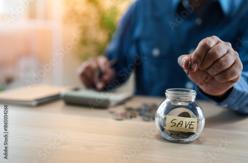 A man hand putting coins into glass bottle saving bank for account save money. Planning step up, saving money for future plan, retirement fund. A business investment-finance accounting concept.