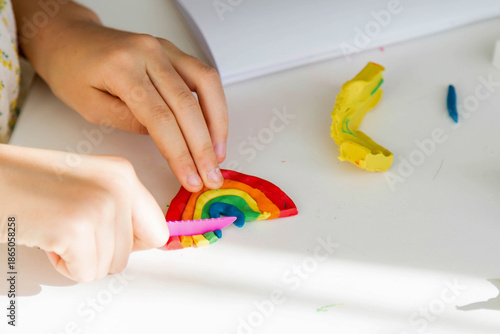 Child hands sculpt colorful rainbow from modeling clay on white table creative activity learning through play fine motor skills imagination and early childhood development