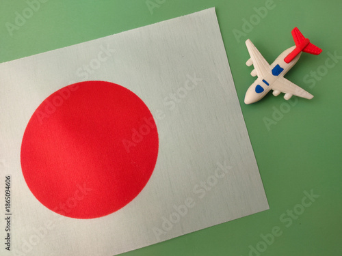 Small toy airplane positioned over the national flag of Japan, symbolizing air travel to the country