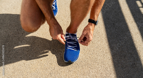 Fotografie Close-up of male runner tying running shoes before jogging.