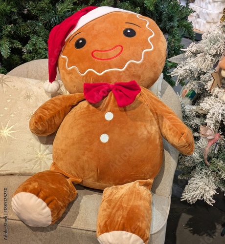 Muñeco de hombre de pan de jengibre, con sombrero de Santa Claus, sentado en un sillón junto a un árbol de navidad 