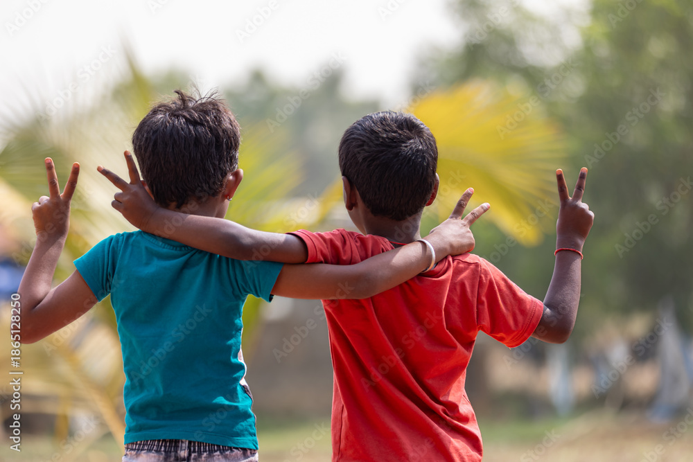 Fototapeta premium Two small boys are hugging together, with gestures of victory.