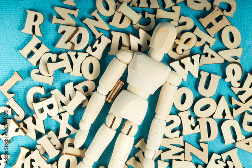 A wooden figure is surrounded by a pile of letters