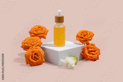 cosmetic bottle with a dropper on a white podium with blooming rose flowers around. The concept of natural cosmetics, natural essential oils and skin care products