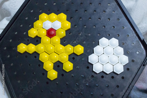 Close-up of child's hands playing with hexagonal mosaic puzzle on a black board.
