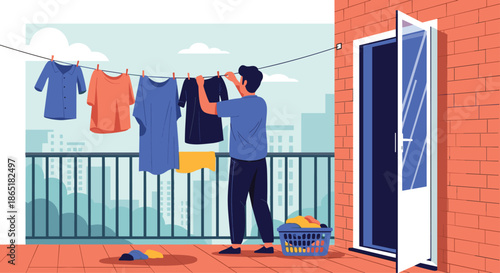 Young man doing laundry, hanging wet clothes on a clothesline to dry on his apartment balcony with a city view.
