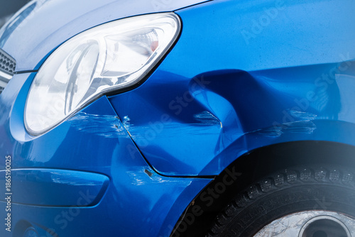 blue car with scratched and dented front fender panel.