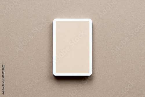 A flat lay image of a deck of cards (mockup) with a beige back and white border, placed centrally on a brown paper background, giving a simple and natural feel.