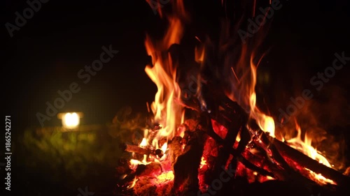 Close up of cozy campfire and light lantern at night. Bonfire, burning old wood. Active lifestyle, traveling, hiking. Camping vibes and outdoor lifestyle mood
