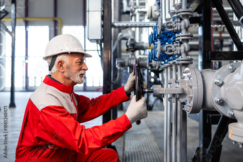Foto Senior industrial worker adjusting valve in processing plant
