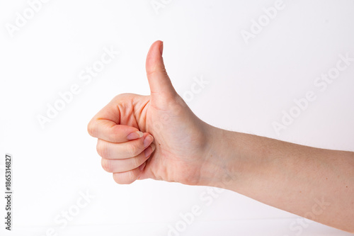 Hand giving a thumbs up gesture in a plain setting