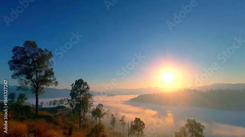 Bright morning sun illuminates layers of low hanging clouds above rolling hills and scattered trees.