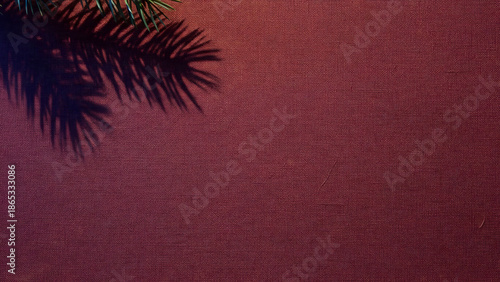 Subtle fir branch shadow on a rich textured red background, evoking a festive holiday mood