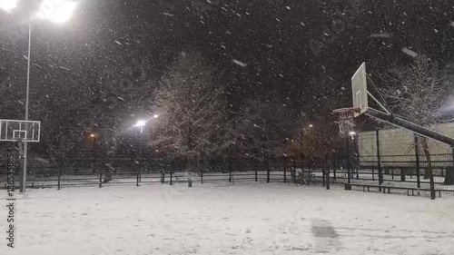 Snowfall on outdoor basketball court winter weather