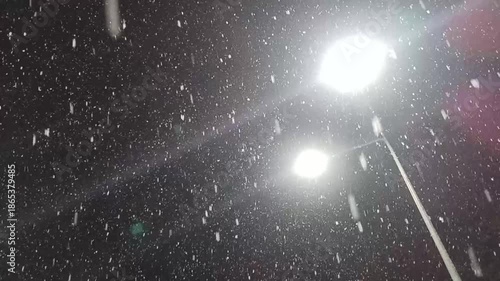 Night snowfall viewed upward with street light