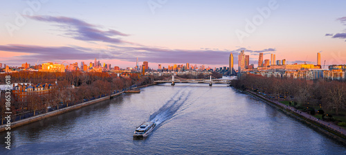 River Thames by Battersea Park with boat and London UK skyline at dusk