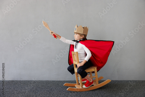 Funny child pretend to be knight. Happy kid having fun at home