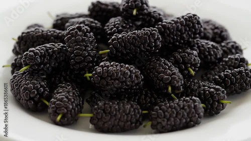 A close-up shot of dark purple mulberries on a white plate
