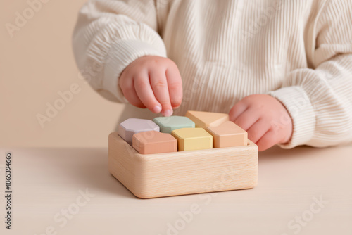 Toddler hand playing with pastel color wooden block toy on table, early childhood development and learning activity with soft natural light and cozy atmosphere