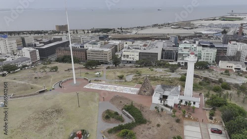 Drone orbits to the left around Donkin Reserve Pyramid and Lighthouse with the coastline in the background on a cloudy afternoon in Gqeberha, Port Elizabeth, South Africa