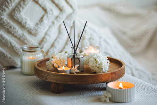 Aroma diffuser, burning candle, blooming hyacinth flowers and perfume on wooden bamboo tray. Cozy home decor, hygge and aromatherapy concept. Comfortable atmosphere, spring delicious fresh smell