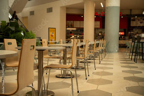 Empty food court seating area with tables and chairs arranged neatly