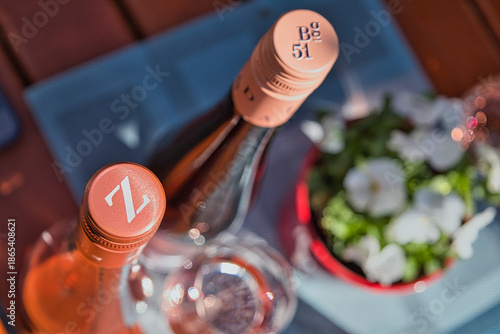 Bild auf Leinwand Zwei Flaschen gekühlter Roséwein auf einem rustikalen Holztisch neben Blumen, So