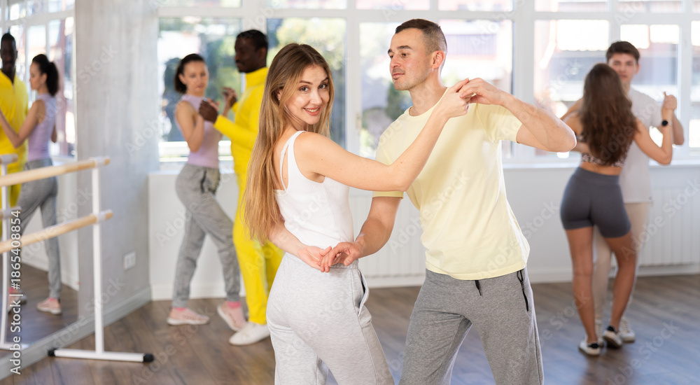 Fototapeta premium Couple of young guy and young woman dancing latin dances in studio