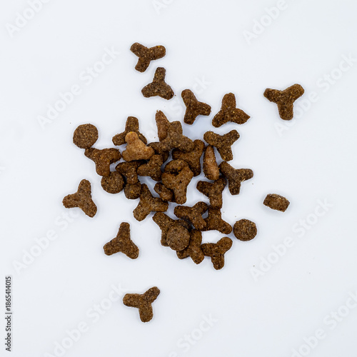 Dry pet food kibble scattered on a clean white background. Crunchy dog or cat food pieces in different shapes, isolated with copy space. Pet nutrition, animal care.