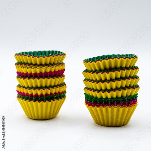 Stacks of colorful paper cupcake liners isolated on a white background. Baking supplies concept related to cupcakes, muffins, homemade desserts, party preparation, and food styling. 