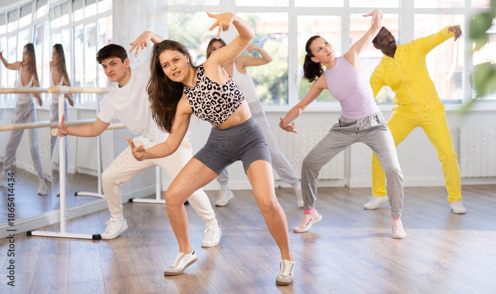 Fototapeta premium Active young woman practicing hip-hop dance in training hall during group dancing classes