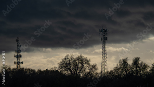 Принти на полотні Industrial cell towers stand tall against a gathering winter storm