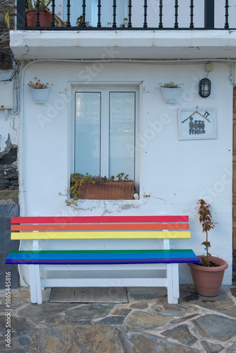Banco pintado con la bandera arco iris en la entrada de una vivienda.