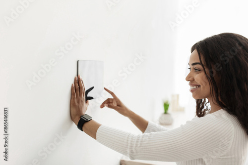 Wallpaper Mural African american woman using digital tablet with blank screen on wall with smart home control system app, adjusting house automation processes and settings. Innovative technology concept. Torontodigital.ca