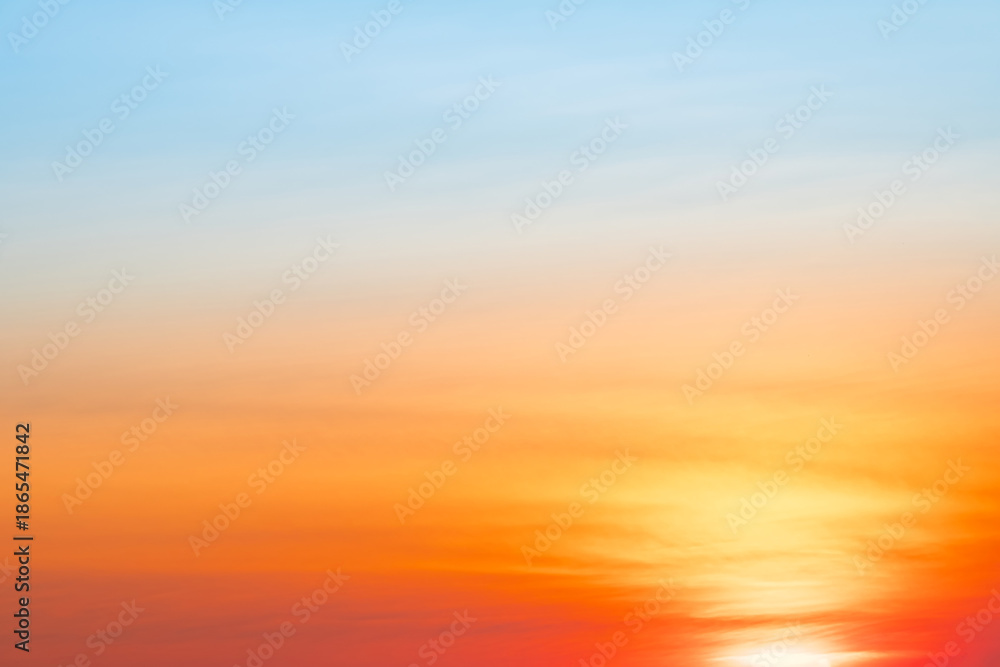 Obraz premium Sunset or sunrise sky with a vibrant gradient of orange, gold, and soft blue. Clear atmosphere with wispy clouds. Peaceful, natural light background. hope, freedom, new day and inspirational Concepts