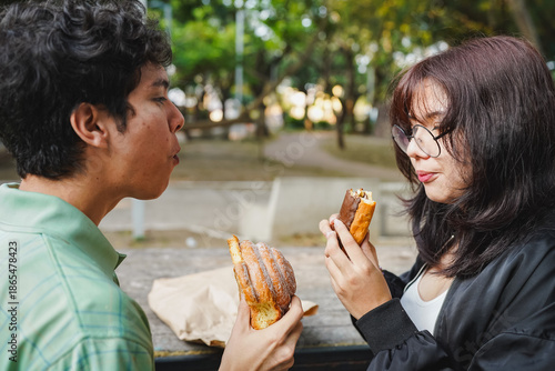 Young couple enjoying simple sweet bread together in park