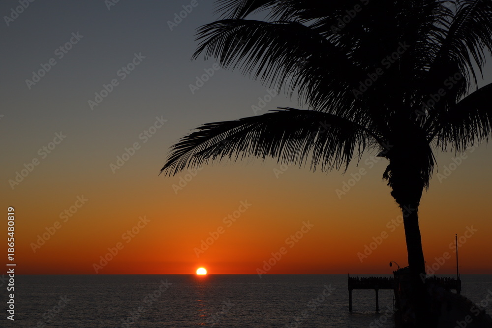 Obraz premium Sunset Over Calm Ocean With Palm Silhouettes and Pier at Dusk, Tropical Seascape scene