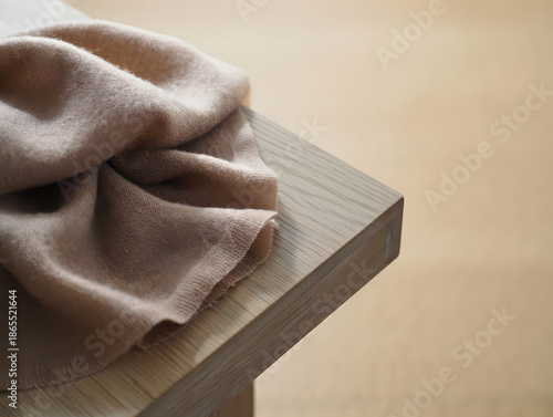 Quiet luxury still life Cashmere scarf on oak surface soft folds neutral palette texture focus serene