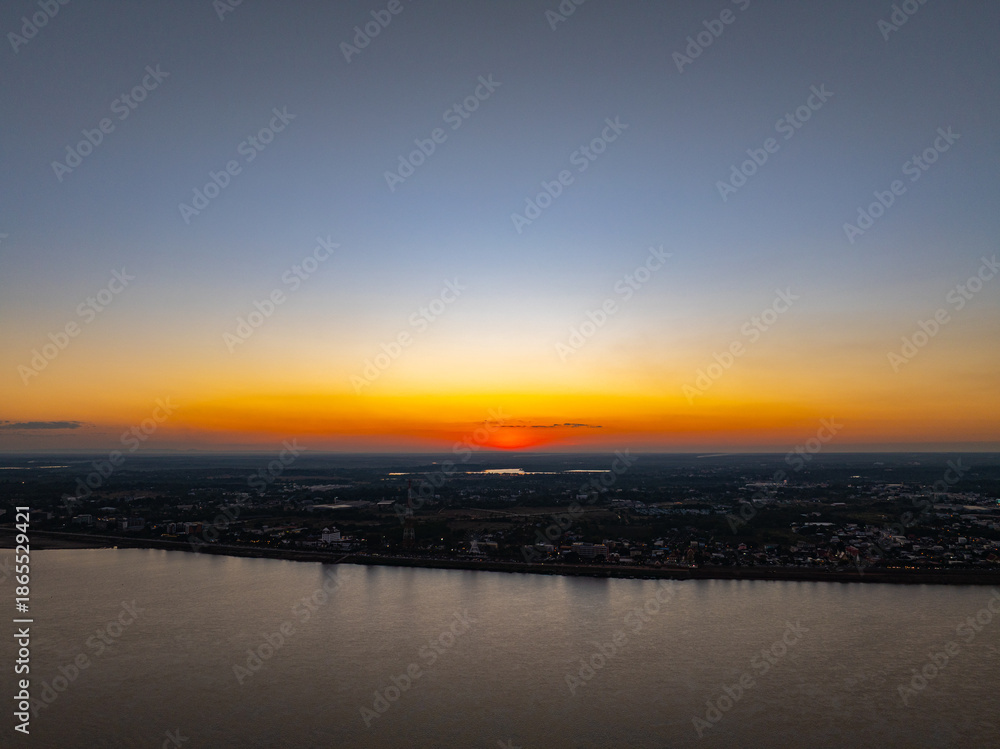 Fototapeta premium Aerial view of The Cost of Burning Crops Beneath a Golden Sun. As the sun sets, smoke from agricultural burning blankets the horizon, transforming natural beauty into a quiet warning of pollution.