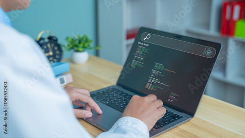 A close-up image of a programmer's hands typing code on a laptop in a modern healthcare workspace, depicting software development, programming, healthcare tech startups, cybersecurity, and digital inn