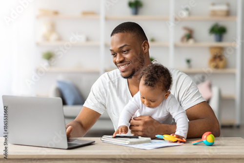 Tableau sur toile Young Black Man Study With Laptop At Home And Taking Care About Baby, African Am