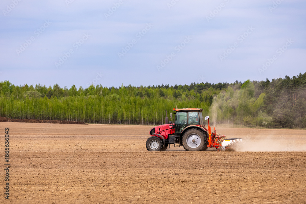 Obraz premium A farmer is seen driving a tractor, sowing seeds and planting crops in the agricultural fields during spring.