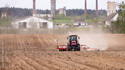 The tractor is used to sow seeds in the field using a specialized device. The tractor is a powerful tool for agricultural work, equipped with seed planters to prepare the soil for planting.