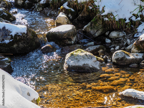 Close up of crystal clear water flowing over pebbles in mountain stream