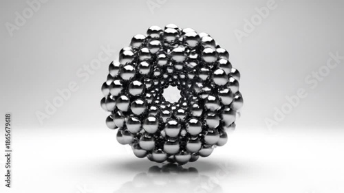A metallic sphere composed of smaller spheres on a white surface with a gradient gray background