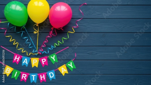 Colorful balloons and happy birthday banner on blue wooden background