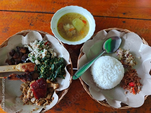 Traditional meal served on woven plates with rice and vegetables on a wooden table